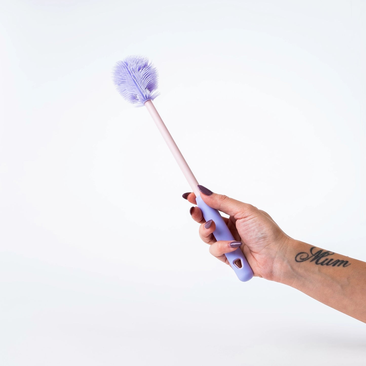 Hand holding a purple brush against a white background