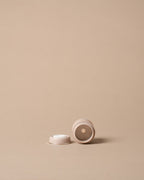 a small bottle cap shown on a solid beige background with ample negative space.