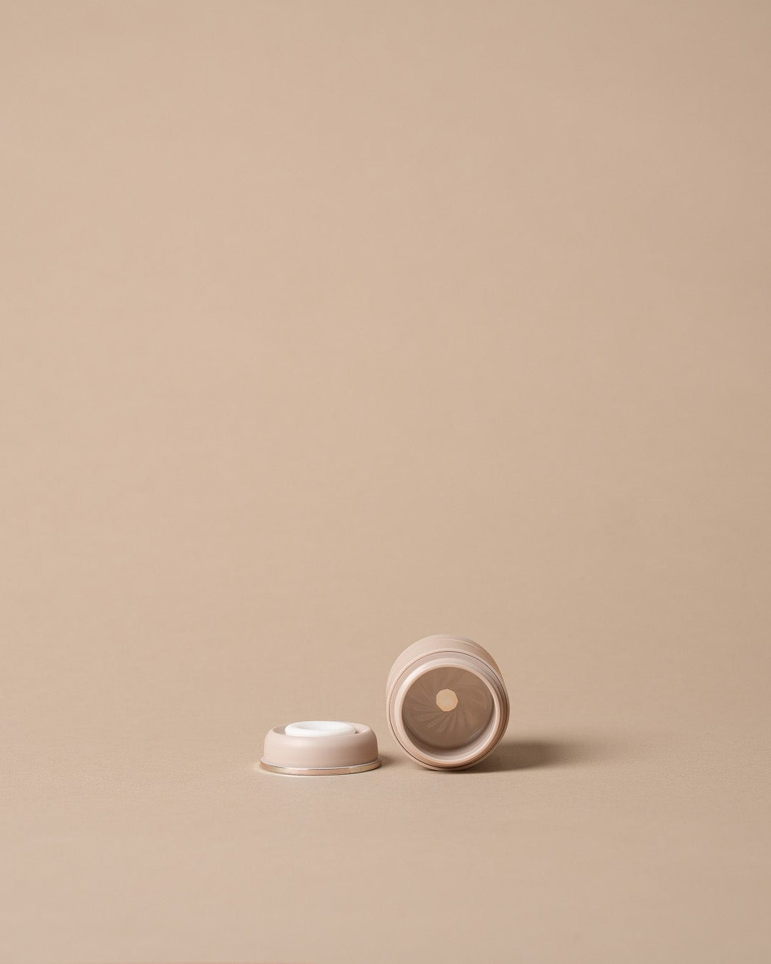  a small bottle cap shown on a solid beige background with ample negative space.