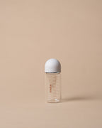 A small clear baby bottle with a white cap, standing upright on a warm beige background. The bottle has red measurement markings and the brand name 'miso' printed vertically on the side.
