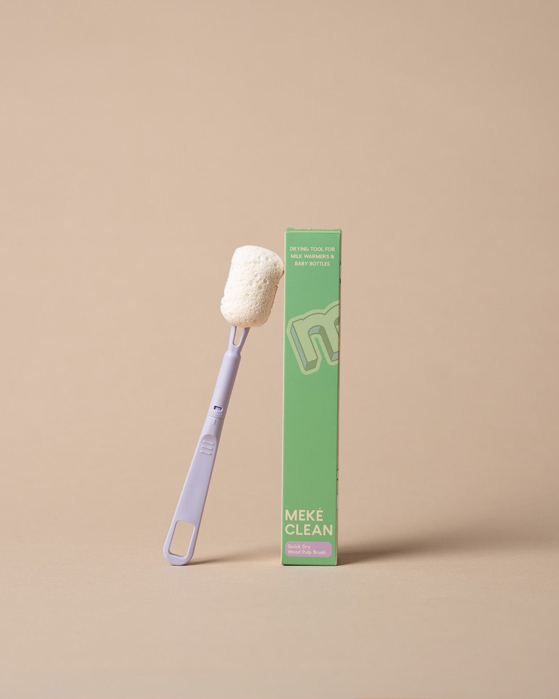 A light purple-handled Meke Clean bottle brush with a white bristle head stands next to its green packaging box on a solid beige background.