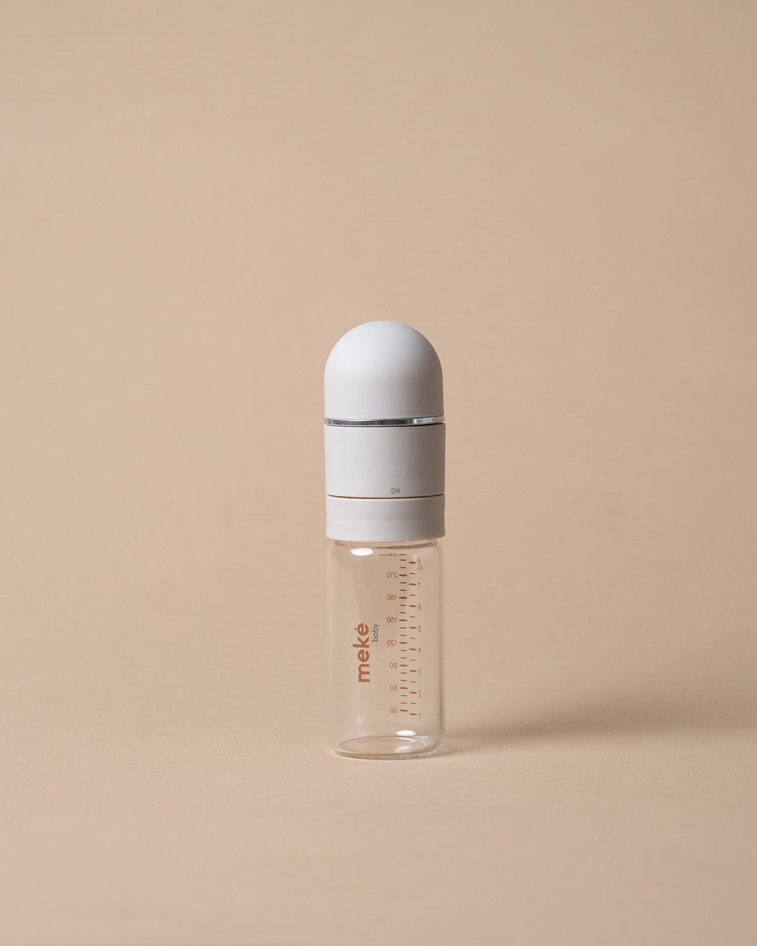 A small clear glass baby bottle with a white cap and a white collar, featuring red measurement markings and the brand name 'miso' printed on the side, set against a solid beige background.