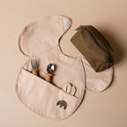 Travel feeding kit with bib, utensils and storage pouch laid out