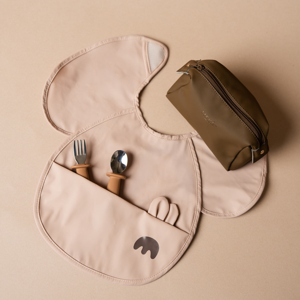 Travel feeding kit with bib, utensils and storage pouch laid out